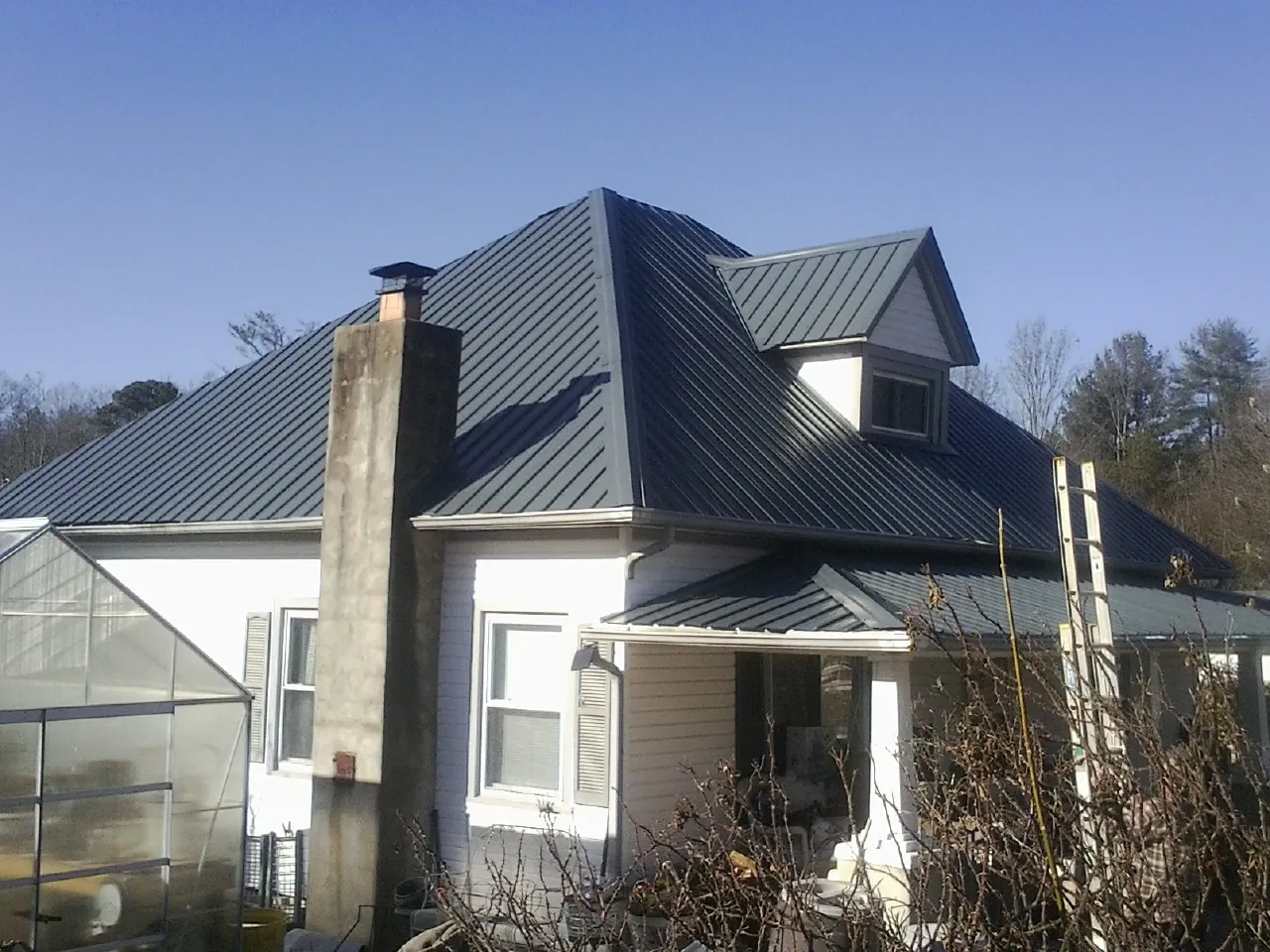 Dark blue standing seam metal roof on a white farmhouse with dormer — Slate & Tile Roof Repair by Roofing Brothers in Candia