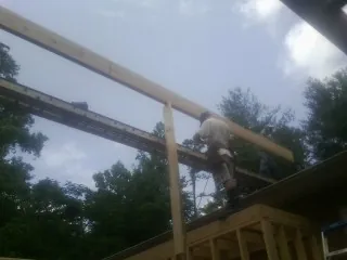 Carpenter setting a ridge beam over a new addition frame — Ice Dam Removal by Roofing Brothers in Candia