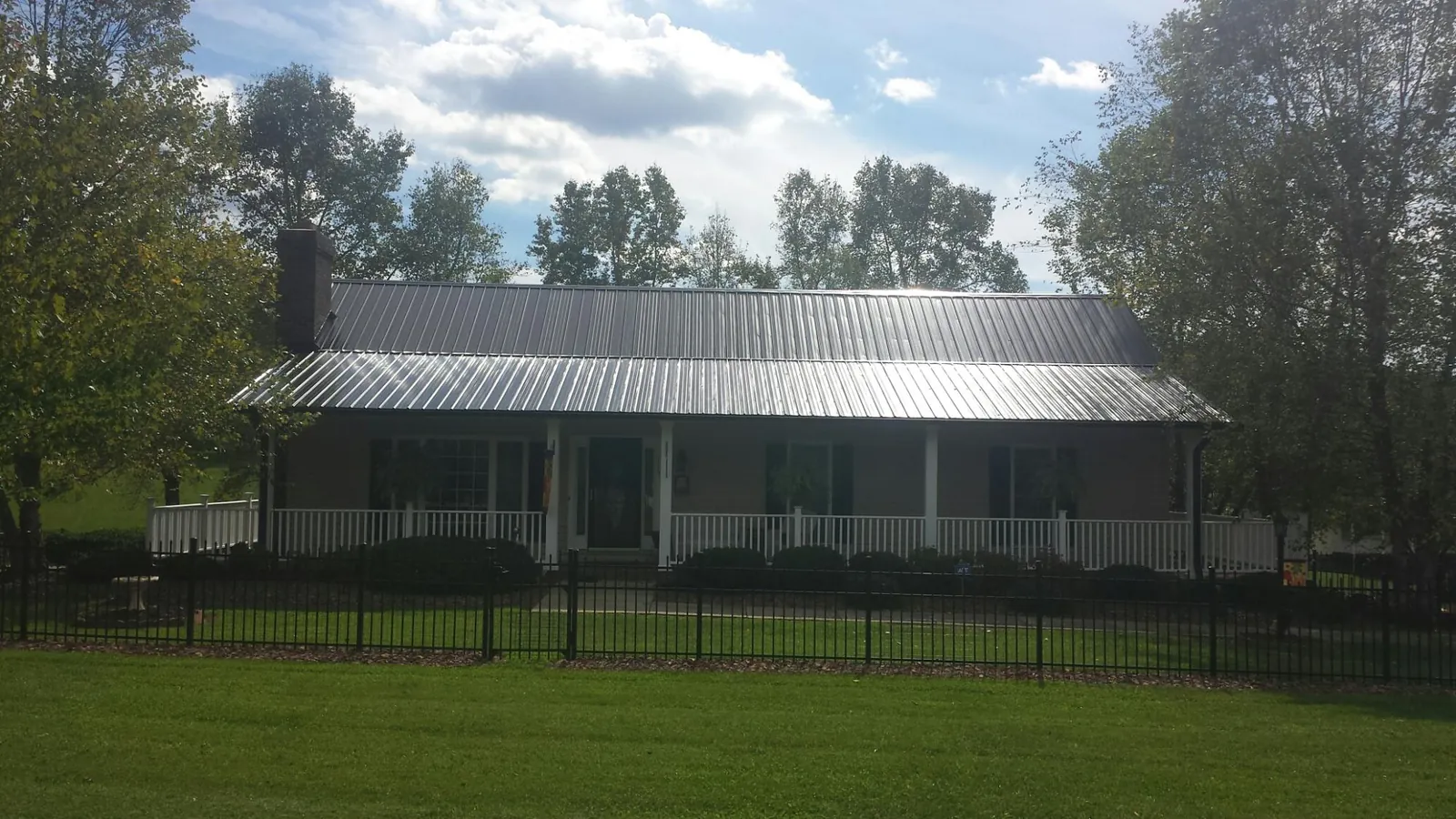Gray metal roof on a brick ranch with a full width front porch — Gutter Guard Installation work by our crew in Candia