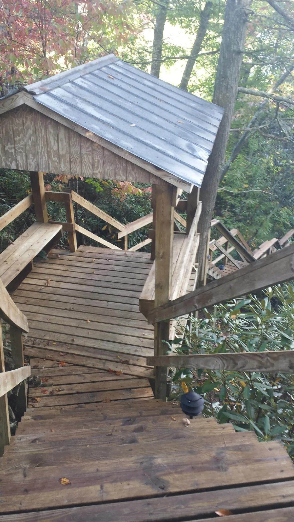 Metal roofed shelter over wooden steps on a wooded walkway — Skylight Repair & Installation work by our crew in Candia