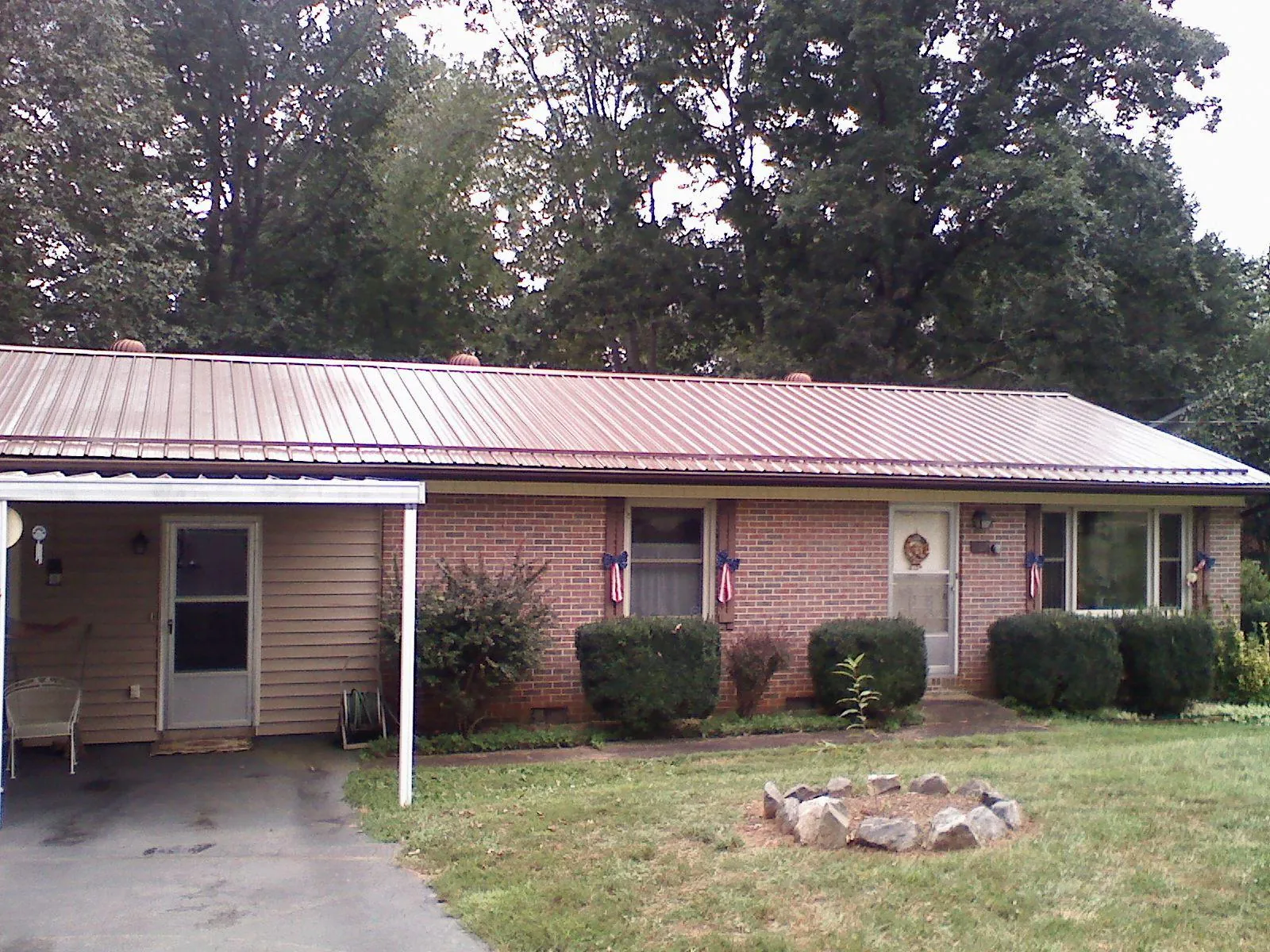 Bronze metal roof and carport on a brick ranch home — Roof Repair work by our crew in Candia