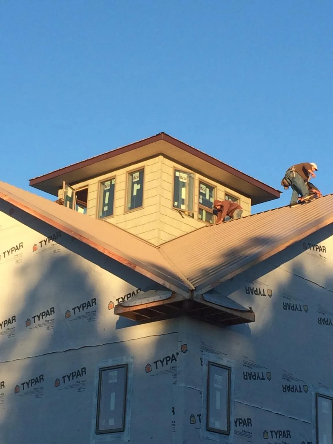 Roofers working around a rooftop cupola on a new metal roof at sunset — Roof Waterproofing in Candia by Roofing Brothers